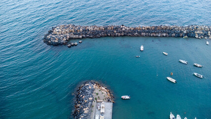 Barca ormeggiata nel porto vista dall'alto, fotografia con drone mostra la massicciata della marina, acqua del mare limpido ed una barca all'ormeggio - obrazy, fototapety, plakaty