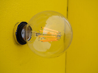 黄色の壁に付いてる丸い電球。