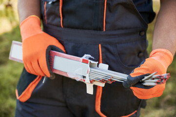 Close up of man hands in orange work gloves holding welding electrodes for solar panel...