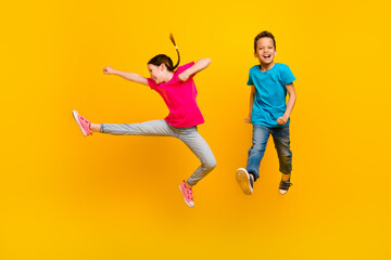 Fototapeta na wymiar Full length photo of two active overjoyed people jumping hand leg kick fight isolated on yellow color background