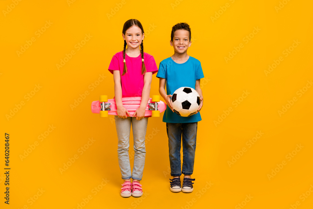 Sticker full size photo of two cute positive schoolkids hands hold skateboard football isolated on yellow co