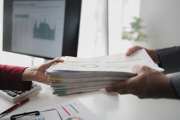 Two company employees handing over papers to each other, marketing staff handing over marketing...