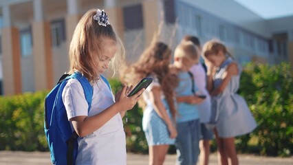 pupils stand in the schoolyard and look at phones. business concept of modern lifestyle training and development. a lifestyle group of students playing on the phone in the backyard of the school