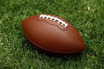 American football ball on green grass background