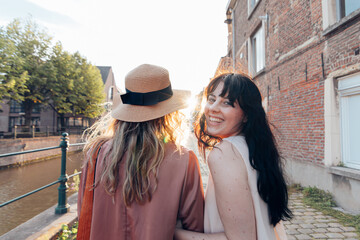 smiling woman walking with her friend on weekend in city trip
