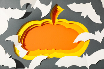 Paper pumpkins and bats on gray background, top view