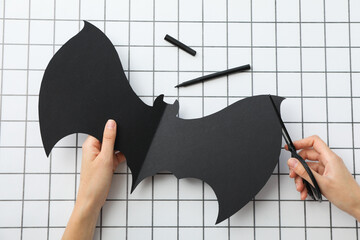 Paper bat and scissors in female hands on light background, top view