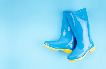 Pair of blue rubber boots on light blue background, top view with empty space for your text.