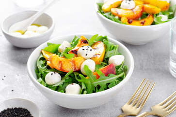 Grilled Peach Salad with Arugula and Mozzarella on Bright Concrete Background