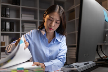 Asian woman sitting in the office working overtime in the middle of the night, employee working overtime to get work done on time. The concept of overtime and hard work of company employees.