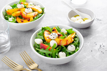 Grilled Peach Salad with Arugula and Mozzarella on Bright Concrete Background