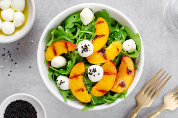 Grilled Peach Salad with Arugula and Mozzarella on Bright Concrete Background