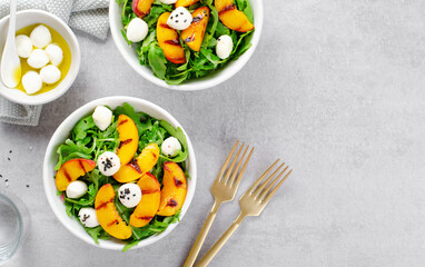 Grilled Peach Salad with Arugula and Mozzarella on Bright Concrete Background