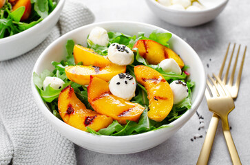 Grilled Peach Salad with Arugula and Mozzarella on Bright Concrete Background