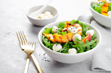 Grilled Peach Salad with Arugula and Mozzarella on Bright Concrete Background