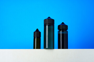 Black electronic cigarettes liquid bottles on blue background