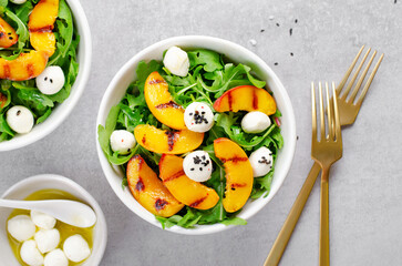 Grilled Peach Salad with Arugula and Mozzarella on Bright Concrete Background