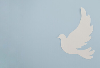White paper origami bird on blue background. World Day of Peace. Day Against Humiliation. International Day Of Human Fraternity. International Day of Living Together in Peace