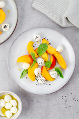 Grilled Peach Salad with Mozzarella Pearls on Bright Concrete Background