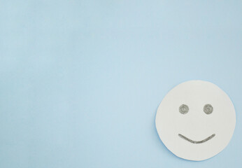 Smiley from white paper on blue background. World Day of Peace. Day Against Humiliation....