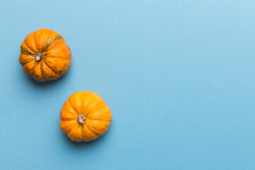 Autumn composition of little orange pumpkins on colored table background. Fall, Halloween and Thanksgiving concept. Autumn flat lay photography. Top view vith copy space