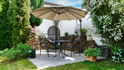 Gartenterrasse mit Hängesessel, Sonnenschirm und Sitzmöbel in einer Gartenecke mit...