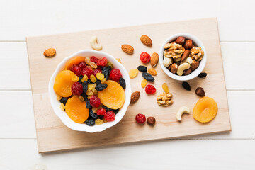 healthy snack: mixed nuts and dried fruits in bowl on table background, almond, pineapple, cranberry, cherry, apricot, cashew