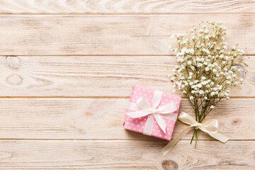 Gift or present box and flower gypsophila on light table top view. Greeting card. Flat lay style with copy space