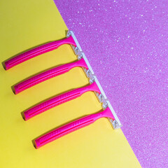Four razors on yellow and sparkle pink background. Close up, flat lay, empty space for text - 640221267