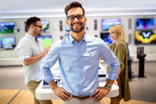 Happy seller man helping to people to buy a new digital smart devices in tech store.