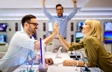 Sales consultant advises people who chooses new digital devices in store. Professional consultation
