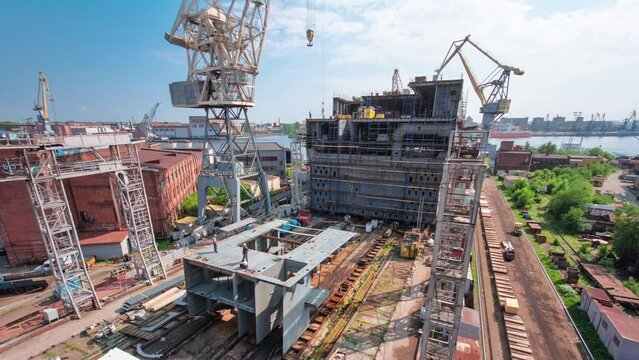 The construction of a large ship on a shipyard with cranes timelapse from above. A fragment of the case in the workshop of the plant. Metal frame during assembly