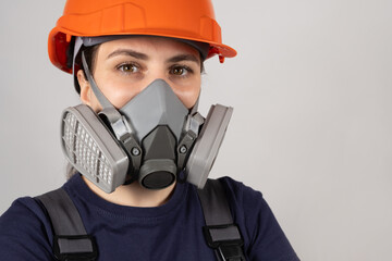 A woman wears a protective respirator with dust and gas filters on a white background.