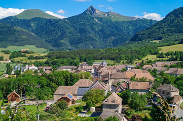 Fototapeta na wymiar Beautiful French village against the background of mountains and blue sky in the Alps of Haute-Provence. Scenic view of Isère, the Percy village Trièves, Regional Natural Park of Vercors