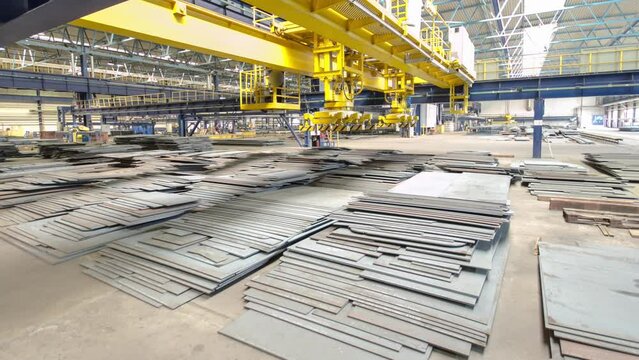 Factory workshop with lifting crane device timelapse hyperlapse, lift loads using lifting magnet, mechanical workshop, metal sheets structures on the floor of plant.