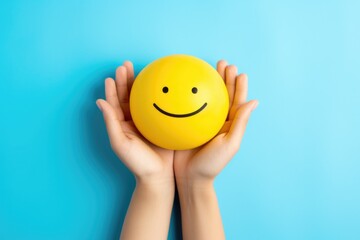 a person holding a yellow smiley face ball