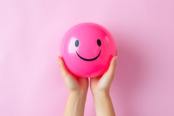 a person holding a pink ball with a smiley face on it