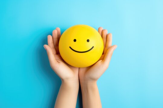 a person holding a yellow smiley face ball