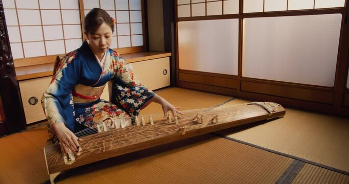Authentic Japanese Koto Player Practising the Art of String Music in Her Traditional Home. Musician in Blue Kimono Using a Long Japanese Board Zither with 13 Silk Strings and Movable Bridges