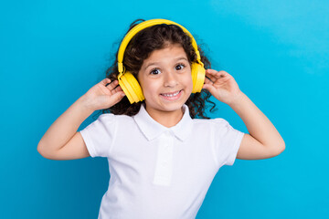 Photo of cute kid girl listen headset enjoy playlist with fairytale audiobook isolated blue color background
