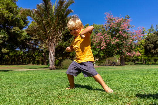 little blond boy somersaults in the park on the green grass