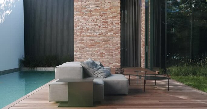 Comfortable couch with pillows and coffee table near swimming pool outside at backyard of modern cottage house. Cozy terrace for rest and lounge outside