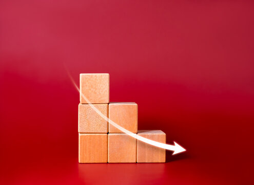 Down arrow on wooden blocks stacked, decrease business graph down step, finance diagram on red background. Financial crisis, bankruptcy, loss investment economic recession sales risk concepts.