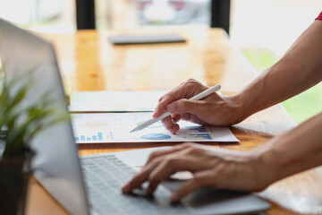 Businessmen holding pens and graph paper are meeting to plan sales to meet targets set for next year.