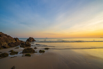 Beautiful sunrise on the beach with rock and sand.
