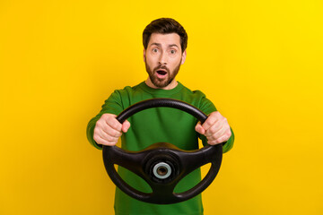 Photo of young surprised funny guy hold steering wheel crazy wear green shirt traffic automobile crash isolated on yellow color background