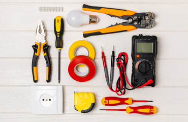 Electrician equipment on a wooden background with copy space.Top view.Electrician tool set.Multimeter, tester,screwdrivers,cutters,duct tape,lamps,tape measure and wires.Flet lay.Concept building © Avocado_studio
