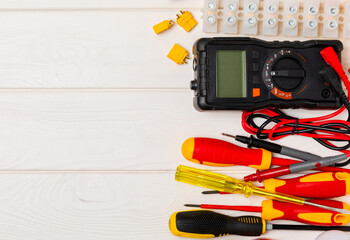 Electrician equipment on a wooden background with copy space.Top view.Electrician tool set.Multimeter, tester,screwdrivers,cutters,duct tape,lamps,tape measure and wires.Flet lay.Concept building © Avocado_studio