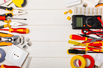 Electrician equipment on a wooden background with copy space.Top view.Electrician tool set.Multimeter, tester,screwdrivers,cutters,duct tape,lamps,tape measure and wires.Flet lay.Concept building © Avocado_studio
