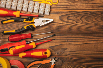 Electrician equipment on a wooden background with copy space.Top view.Electrician tool set.Multimeter, tester,screwdrivers,cutters,duct tape,lamps,tape measure and wires.Flet lay.Concept building © Avocado_studio